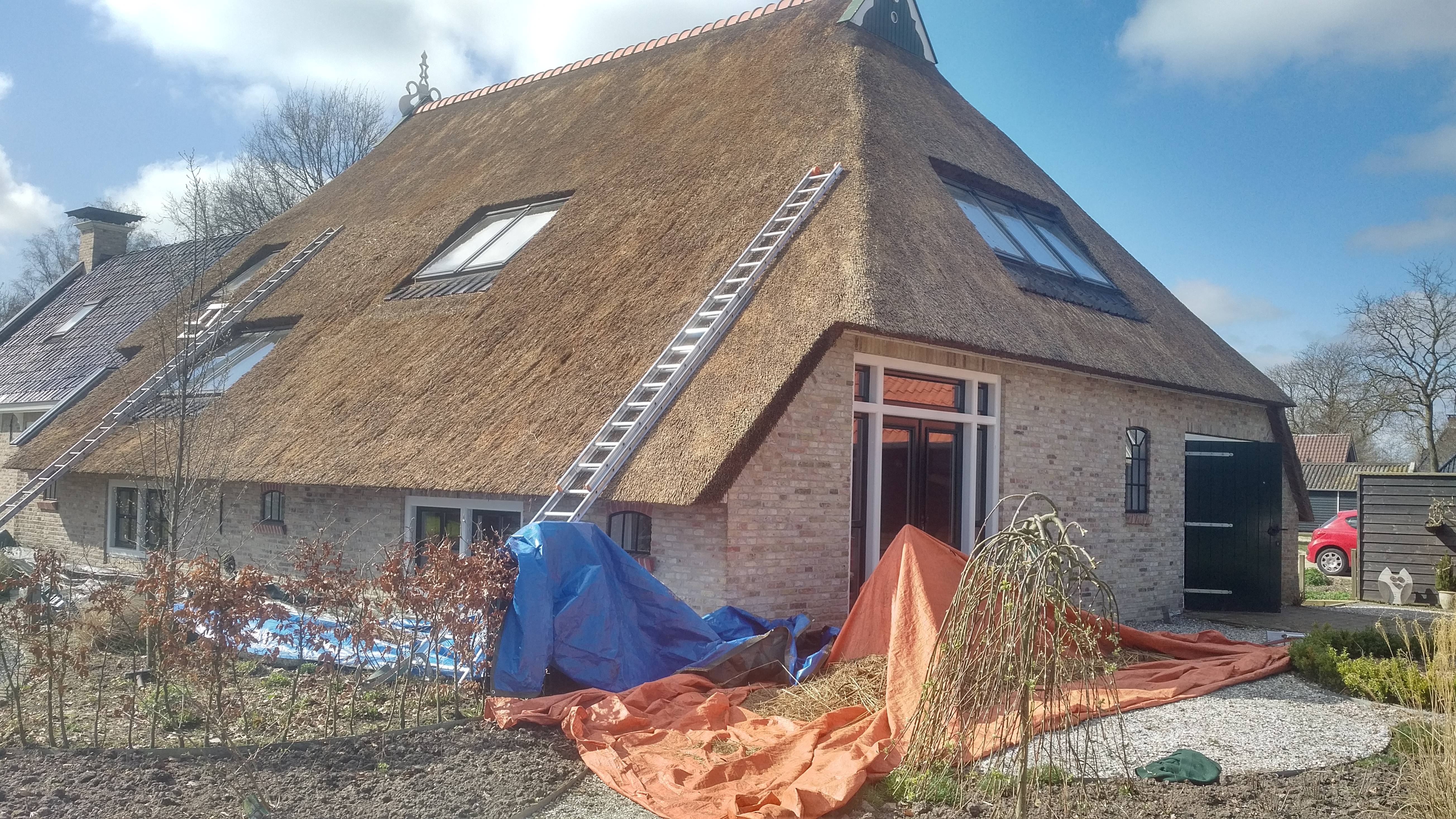 Rieten dak schoonmaken in uitvoering met ladder en beschermzeilen – Alting Rietbeheer